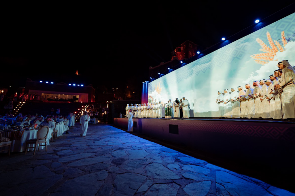 Big LED screen with branding on it on a raised stage so people can watch with nice ambient blue lighting shining down on it